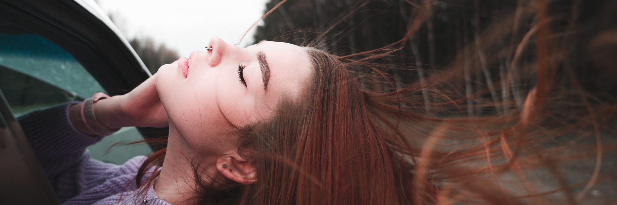 ilya-shishikhin-unsplash-missiondevie jeune femme épanouie et libre d'avoir trouvé sa mission de vie, penchée par la fenêtre du voiture qui roule